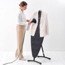 Person using a handheld garment steamer on a blazer hanging from the Brabantia Steam & Iron Board in upright position.