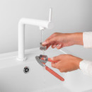 Brabantia Tasty+ garlic press being rinsed under running water, demonstrating the removable press chamber for easy cleaning.