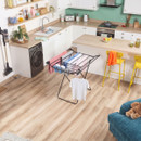 Black freestanding clothes drying rack loaded with laundry in a bright kitchen and utility room setting.