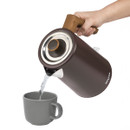 Salter Toronto rapid boil kettle pouring hot water into a grey mug, showing the ergonomic wood-effect handle and precision spout.
