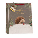 Large Christmas gift bag with hedgehog in a snowy winter scene, gold foil “Christmas Wishes” text, holly and evergreen accents, red rope handles and matching gift tag.