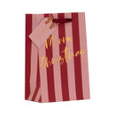 Small Christmas gift bag with pink and burgundy striped design, gold foil “Merry Christmas” script, burgundy ribbon handles and coordinating gift tag with decorative bow.