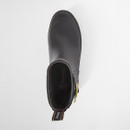 Top view of a black Barbour ankle wellington boot with a rounded toe, branded pull tab, tartan lining, and gold-tone buckle detail on a white background.