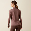 Back view of a model wearing a twilight mauve Ariat half-zip performance pullover with a stand collar, raglan sleeves, and a fitted silhouette, paired with brown riding tights.