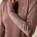 Close-up of the twilight mauve Ariat half-zip pullover highlighting the tonal Ariat logo printed along the sleeve, thumbhole cuff, and chest logo.