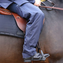 Waterproof riding chaps worn in the saddle, demonstrating the ergonomic fit, full-length zip design and weatherproof protection that keeps legs dry while riding in wet conditions.