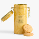 Cartwright & Butler Cheddar & Chilli Shortbread Rounds in an open yellow clip-lid tin with two savoury cheddar shortbread biscuits, isolated on a white background.