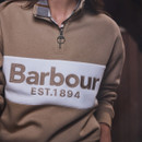 Close-up of the Barbour women's beige quarter zip sweatshirt featuring the embroidered Barbour EST.1894 logo, contrast chest panel and ring zip pull.