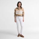 Full-length view of the Barbour women's beige quarter zip sweatshirt styled with white jeans, loafers and a checked shirt layered underneath.