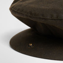 Close-up of the Barbour olive wax flat cap showing the reinforced peak with concealed press stud fastening and waxed cotton fabric.
