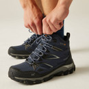 Close-up of hands tightening the laces on navy blue waterproof hiking boots, highlighting secure lacing system and cushioned ankle support.