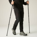 Person using trekking poles while wearing grey waterproof hiking shoes with grippy trail soles for hiking and walking on varied terrain.