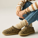 Leopard print mule slippers styled with cream knitted socks, blue jeans and a striped knit jumper for a warm, relaxed indoor look.