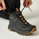 Close-up of a black Regatta waterproof hiking boot with speed lacing system being tightened, highlighting secure fit, padded ankle support and grippy outsole.
