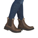 Model wearing brown faux leather Chelsea ankle boots with faux fur trim, elastic side panels, inside zip fastening and chunky tread sole, paired with dark blue skinny jeans.