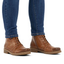 Model wearing brown leather lace-up ankle boots with warm lining, inside zip and comfortable low heel.