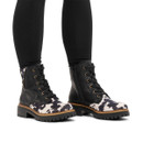 Model wearing Rieker black lace-up ankle boots with cow print pony hair panels, chunky lug soles and inside zip fastening.