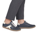 Model wearing Rieker navy lace-up trainers with side zip, white contrast detailing and translucent gum soles