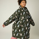 Front lifestyle image of the junior waterproof robe worn zipped up, showcasing the oversized fit, hood, and playful all-over print.