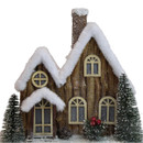 Close-up of a rustic wooden Christmas house decoration featuring snow-covered roofs, glitter accents, bottle brush trees and festive winter details.