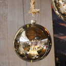 Close-up of a shiny pre-lit silver bauble with a rustic rope hanger and reflective finish.