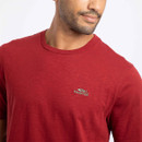 Close-up of the Weird Fish embroidered fish logo on the chest of the red crew neck T-shirt, highlighting the soft fabric and premium finish.