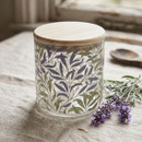 William Morris Willow Bough small glass storage canister with a natural bamboo lid, featuring the classic blue and green leafy pattern, styled on a linen tablecloth with fresh lavender.