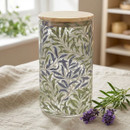 William Morris Willow Bough large glass storage canister with a natural bamboo lid, featuring the iconic blue and green leafy design, displayed on a linen tablecloth with lavender sprigs.