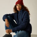 Woman sitting wearing a Regatta women's navy longline borg fleece with a red knitted beanie.