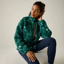 Model sitting while wearing the Regatta women's green printed borg fleece jacket with a high collar.