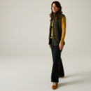 Full-length view of a model wearing the Regatta women's Dark Khaki borg bodywarmer over a mustard long sleeve top and black trousers.
