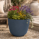 Deep sea blue embossed leaf planter filled with colourful flowering plants and trailing ivy, displayed in a contemporary garden setting.