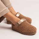 Pair of women's camel teddy fleece clogs with adjustable beige heel straps, thick cushioned soles and a warm slip-on design worn with loungewear.