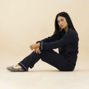Woman wearing navy pyjamas and grey heart print slippers with soft faux fur lining, relaxing indoors in a cosy loungewear setting.