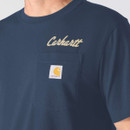 Close-up of a navy Carhartt T-shirt featuring a chest pocket with woven logo patch and beige Carhartt script print.