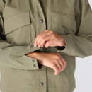 Close-up of a women’s olive green Carhartt jacket showing the snap-adjustable cuffs and oversized flap chest pockets.