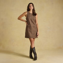 Brown checked sleeveless mini dress worn with western-style boots, showing its fitted silhouette and above-the-knee hem.