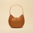 Back view showcasing the curved saddle-inspired silhouette, warm tan finish, structured trim and slim shoulder strap.