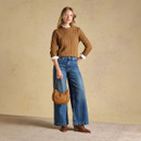 Full-length styling shot showing the cable knit jumper layered over a crisp shirt and paired with wide-leg denim.