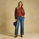 Full-length styling of the burnt orange cable-knit jumper layered under a checked blazer with wide-leg jeans and brown ankle boots.