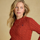 Close-up of a model wearing a burnt orange cable-knit jumper with a crew neck, ribbed trim and small embroidered chest logo.