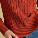 Close-up of the burnt orange jumper, highlighting the textured cable knit and deep ribbed hem and cuffs.