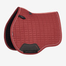 Red LeMieux GP saddle pad with square quilting, contrasting piping and black protective girth panel on a white background.
