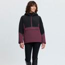 Woman modelling a black and plum LeMieux hooded jacket with large front pocket and black riding breeches.