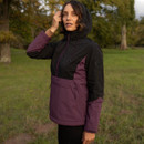 Woman modelling a black and plum LeMieux outdoor jacket with the hood raised in a green park.