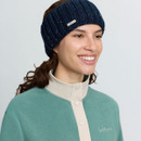 Woman wearing a navy LeMieux knitted headband with subtle sequin detailing and metal logo badge.
