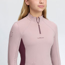 Close-up of the pale pink LeMieux girls’ riding top showing the quarter-zip collar, contrast side panel and chest branding.