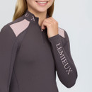 Close-up of the LeMieux girls’ quarter-zip riding top showing pale pink shoulder panels, branded collar and large LeMieux sleeve logo.