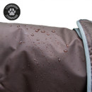 Close-up of brown Stormguard dog coat fabric with water droplets beading on the waterproof outer material and reflective edging.