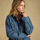 Model wearing a denim shirt with button-up details and two front pockets against a neutral background.
